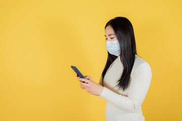 Portrait of asian woman wears using a smartphone on yellow background