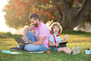 Pupil with teacher learning outdoor by studying online and working on tablet in park. Portrait of happy family father and his son using laptop outside.