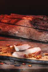 Raw pork neck smoked ham at home in smoker, traditionally rustic dish, on a hand-made wood derving or cutting board