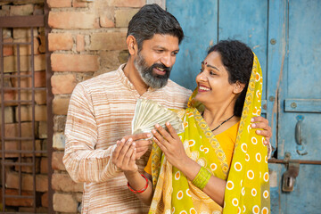 Happy rural couple holding indian rupees notes, Smiling Beard man give money to his wife.