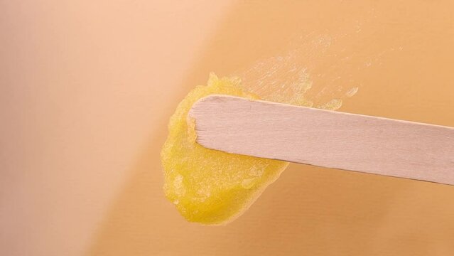 A smear of orange sugar body scrub on a colored background, top view. Beauty treatments and spa.