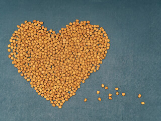 Heart made of dry pet food on a dark background. The concept of love and care for pets.