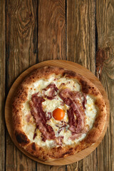 Carbonara pizza with bacon and egg on wooden background