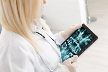 Discussing issues. Cropped shot of a professional dentist showing jaws and teeth x-rays to his patient using a digital tablet