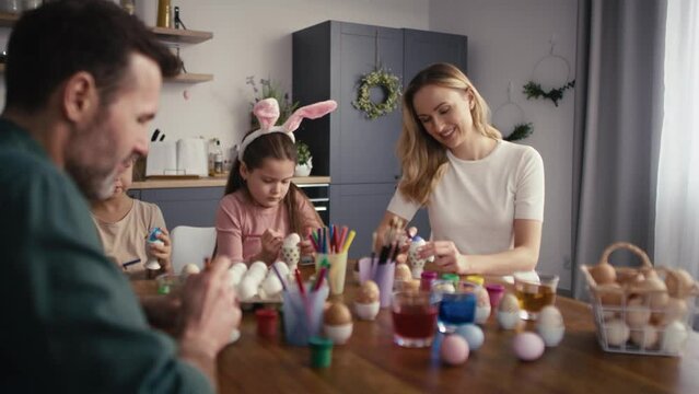 Cheerful caucasian family of four people decorating easter eggs at home. Shot with RED helium camera in 8K   