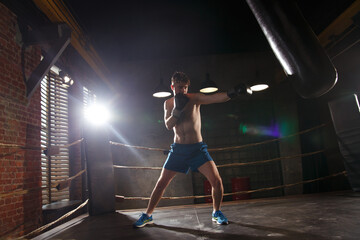 Fototapeta na wymiar A boxer trains in the gym strikes a punching bag.