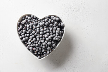 Frozen black currant in heart shaped plate isolated on white background. View from above. Concept love eco organic food. Summer harvest.