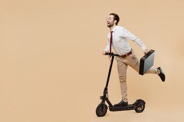 Full size side view young employee business man corporate lawyer wear white shirt red tie glasses work in office riding electric e scooter hold briefcase hurry up isolated on plain beige background. - obrazy, fototapety, plakaty