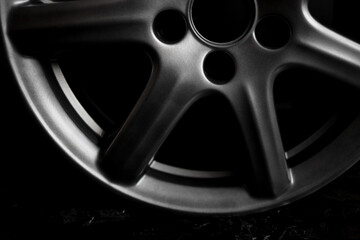 Grey alloy wheel or rim of a car on a black background side view, close-up