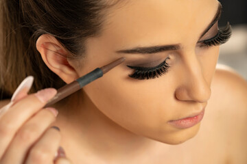 Beauty makeup. Woman shaping eyebrow with brow pencil closeup