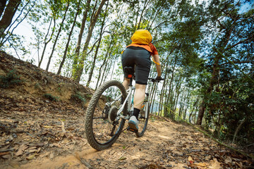Naklejka premium Woman riding bike on mountain top forest trail