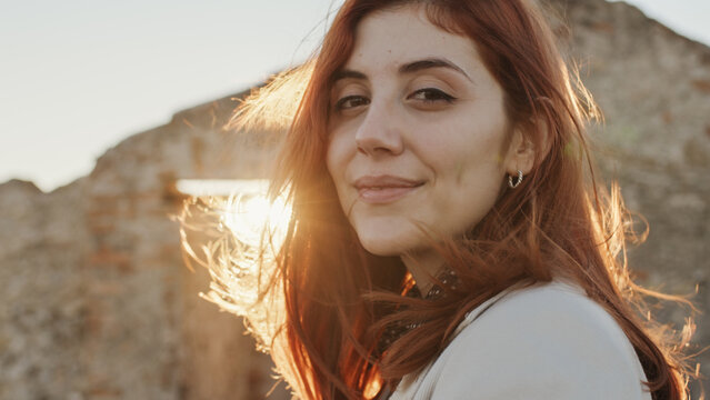 Beautiful girl with white dress explores an ancient Italian castle at sunset