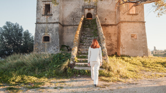 Beautiful girl in white dress enters an ancient castle in the countryside 