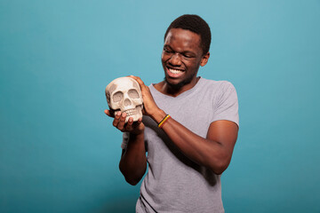 Smiling guy showing human skull bones in front of camera, studying scientific medicine to learn...