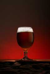 a glass of foamy beer on a counter made of textured wood