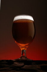 a glass of foamy beer on a counter made of textured wood