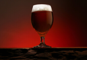 a glass of foamy beer on a counter made of textured wood	