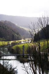 Aerial view of rope bridge near small medieval town Saint-Ursanne with river Doubs and defocus...