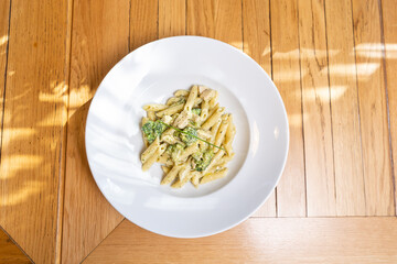 Penne pasta with pesto cream sauce served in a restaurant on a sunny day