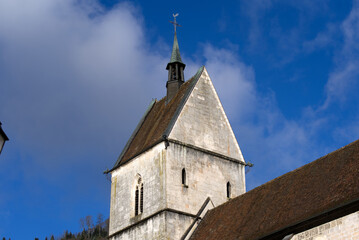 Fototapeta na wymiar Beautiful collegiate church at little medieval town St-Ursanne, Canton Jura, on a sunny winter day. Photo taken February 7th, 2022, Saint-Ursanne, Switzerland.