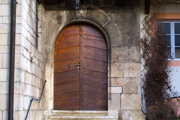 Fototapeta na wymiar Close-up of wooden door at entrance to church on a sunny winter morning at little medieval town St-Ursanne. Photo taken February 7th, 2022, Saint-Ursanne, Switzerland.