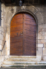 Close-up of wooden door at entrance to church on a sunny winter morning at little medieval town St-Ursanne. Photo taken February 7th, 2022, Saint-Ursanne, Switzerland.
