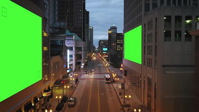 Low over streets with green screens on billboards in a city - Aerial 3D render