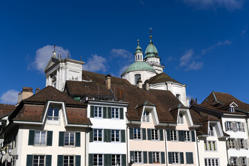 Fototapeta premium Historic colorful house facades at medieval alley with cathedral St. Ursen in the background at the old town of Solothurn on a sunny winter day. Photo taken February 7th, 2022, Solothurn, Switzerland.