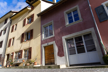 Fototapeta na wymiar Beautiful historic houses with colorful facades at the little medieval town of St-Ursanne, Canton Jura, on a winter morning. Photo taken February 7th, 2022, Saint-Ursanne, Switzerland.