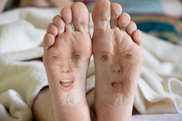 bare feet with girl's face on girl's leg on bed at home, face