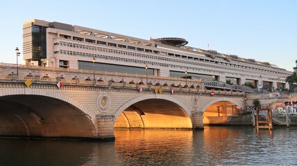 Naklejka premium Ville de Paris, pont de Bercy sur la Seine, au soleil couchant, avec le bâtiment du Ministère de l'Économie et des Finances français en arrière-plan (France)