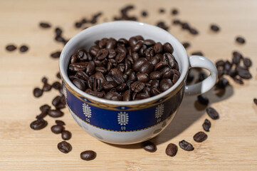 filiżanka z nasionami palonej kawy na drewnianym jasnym tle