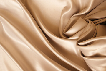 Beautiful elegant wavy beige or light brown satin silk luxury cloth fabric texture, abstract background design. 