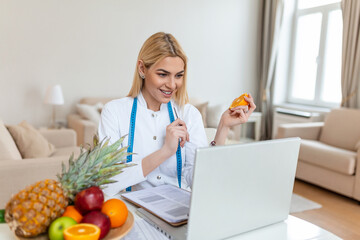 Obraz na płótnie Canvas Smiling nutritionist in her office, she is showing healthy vegetables and fruits, healthcare and diet concept. Female nutritionist with fruits working at her desk.
