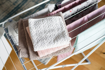 Clean laundry hanging on drying rack indoors