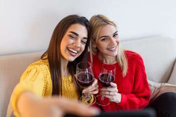 Excited friends taking selfie and laughing. Indoor shot of two emotional caucasian girls. Two adult woman making selfies with funny faces. Two female friends taking a selfie