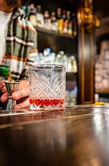 man hand bartender making glass negroni cocktail in bar
