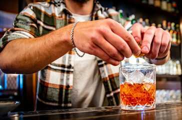 man hand bartender making glass negroni cocktail in bar