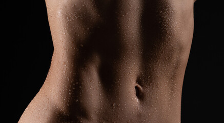 Close up of fit woman torso with sweat on skin after workout. Female with perfect abdomen muscles....