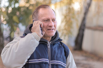 portrait of a happy handsome middle-aged man, 50-60 years old, on a city background, calling on the phone