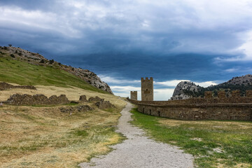 Fototapeta na wymiar A picturesque view with a stormy sky of the Fortress Mountain and the ancient fortress. Genoese Fortress, Sudak, Crimea