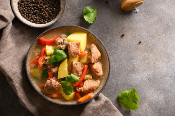 Beef stew with vegetables, potatoes, pepper,carrot in bowl on brown background. European cuisine. Top view.