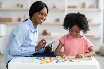 Female psychologist working with little girl at office