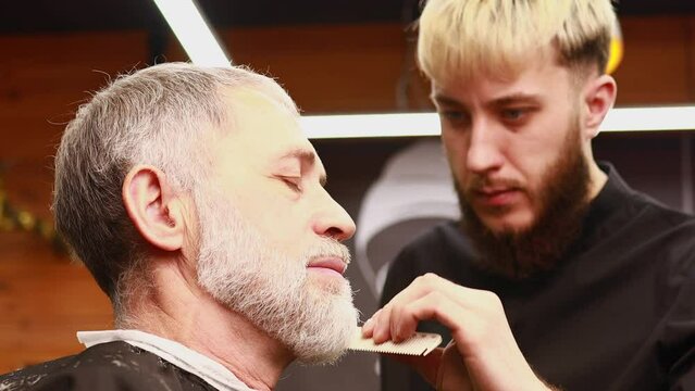 Senior handsome man visiting hairstylist in modern barber shop