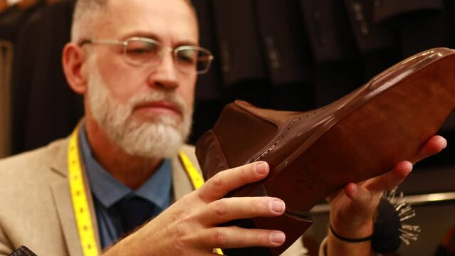 elder good looking man with gray beard wear nice suit at atelier studio and checking the quality of handmade itatian shoe