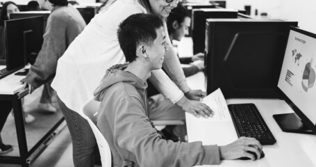 Teacher working with students inside computer class room - Focus on asian head - black and white editing © DisobeyArt