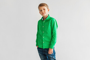 Fototapeta premium Serious Blonde Boy Wearing Green Shirt Posing Over Gray Background
