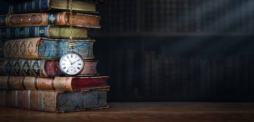Old clock hanging on a chain on the background of old books.  Сlock as a symbol of time a books...