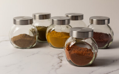 A set of spices for Asian dishes. Ground spices in clear glass jars