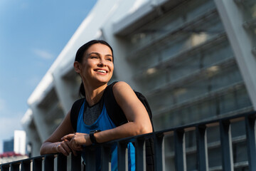 High-spirited sporty Caucasian lady standing by metal railing